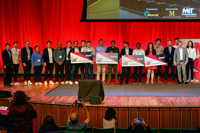 Group of people on stage with four large checks.
