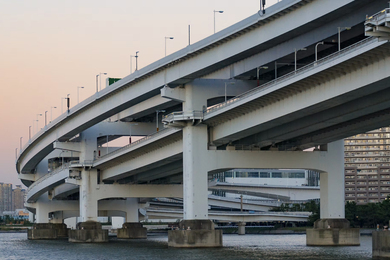 Curved split-level road bridge stands in water beside tall apartment buildings