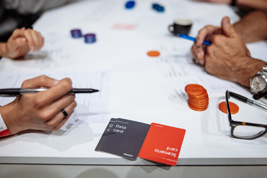 Photo of hands around a table, where people are playing a game with chips and cards