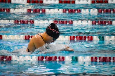 Aria Eppinger plunges forward in the middle of an indoor swim competition. 