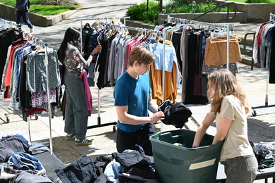 Cameron Dougal works amidst racks of clothing at an outdoor popup sale