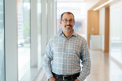 Youssef Marzouk stands in a bright hallway with large windows lined on the left.