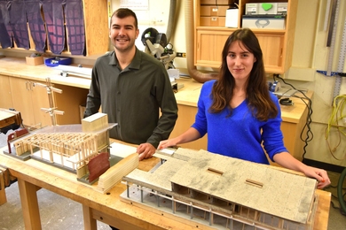 Vincent Jackow and Aleks Banaś stand behind their wood-and-stone model of a building