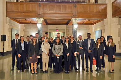 About 20 professionally dressed people pose in a building lobby