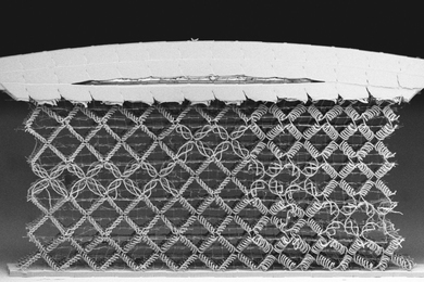 A black and white image of a woven metamaterial, comprised mostly of diamond-shaped cells woven from spiral fibers