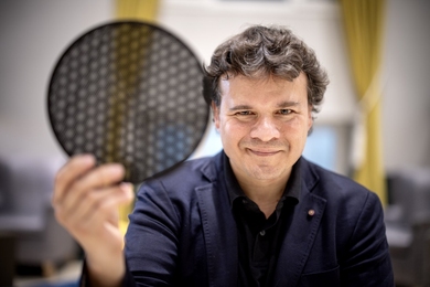 Pablo Jarillo-Herrero holds a translucent black disk comprised of hexagonal cells