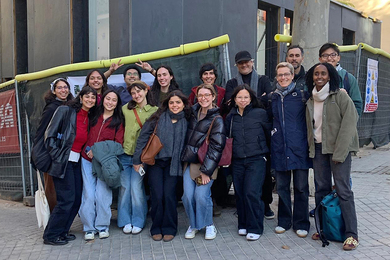 16 people in winter outerwear pose in two lines on a city corner