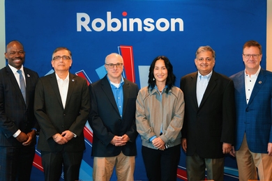 Six people stand in front of a blue event banner, with the word “Robinson” above them.