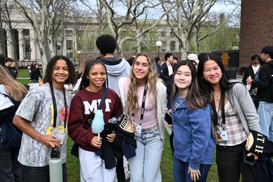 Five MIT students pose together on campus on a spring day