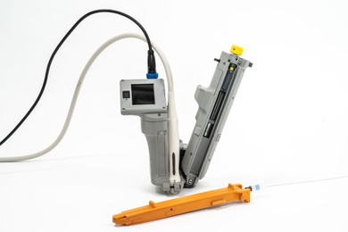 The AI-GUIDE device is a V-shaped foldable unit with a small screen, a power cord, and a flexible catheter tube